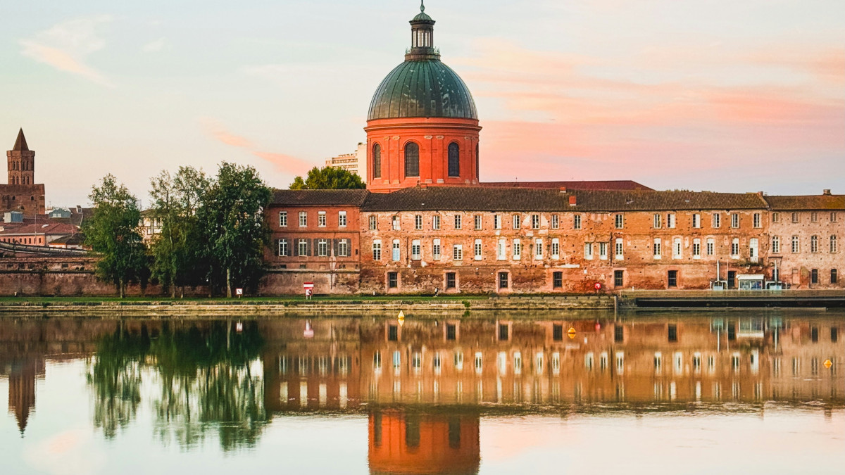 Jolie vue sur la ville de Toulouse avec reflet dans l'eau sous un ciel rose. 